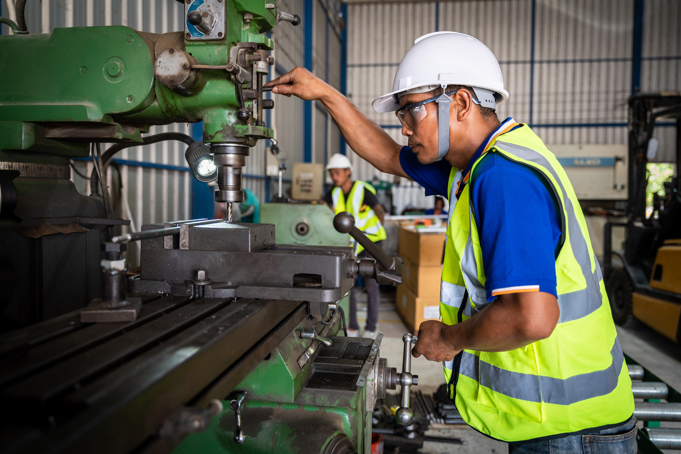 Asian worker wearing safety goggles working at lathe. Safety fir